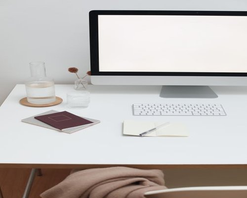 A clean, organized desk setup with a notebook and a glass of water